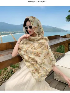 Detailed view of long floral print sunscreen shawl worn as headscarf in beach setting.
