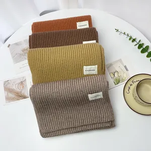 Sciarpe lavorate a maglia a coste in quattro colori caldi su un tavolo bianco