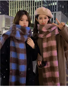 Close-up of two models wearing thick plaid mohair scarves in a cozy winter night setting