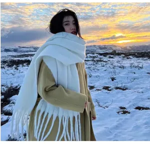 Asian woman wearing a thick white mohair-style scarf with fringes in a snowy landscape