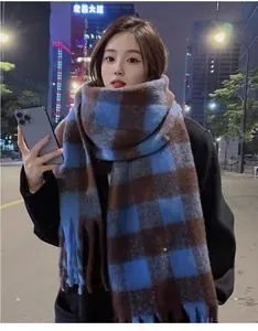 Close-up of a blue and brown checkered mohair scarf worn by a model in a night street.
