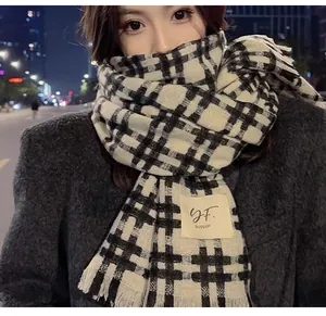 Detailed view of the soft knit texture and brand label on a black and white checkered scarf.