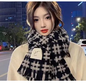 Close-up of a stylish black and beige plaid scarf with a soft tassel trim detail