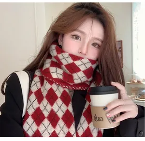 Close-up of a red and white argyle knitted scarf worn by a model holding coffee.