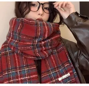 Detailed view of a soft red plaid scarf worn by a model for a stylish winter look.