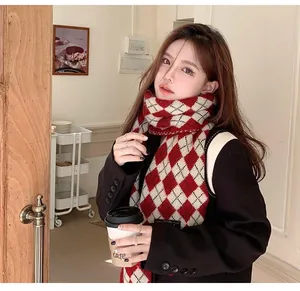 Detailed view of a cozy red and white argyle knit scarf worn by a female model in a cafe.