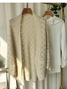 Close-up detail showing the intricate hollow-out diamond knit pattern of the beige shawl