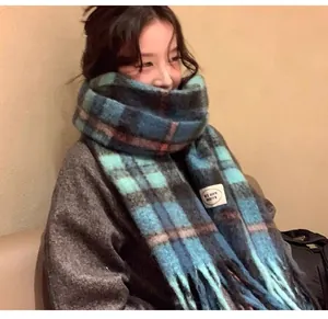 Detail of thick blue plaid mohair winter scarf with long fringe on a female model