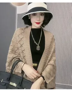 Close-up detail of a khaki hollow diamond knit shawl cardigan worn by an elegant woman