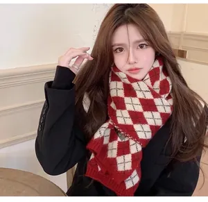 Detailed view of a warm red and white argyle knit scarf worn by a model for winter