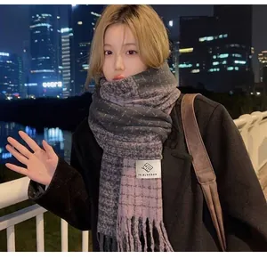 Detailansicht eines weichen lila-grau karierten Schals in einer gemütlichen Winternacht.