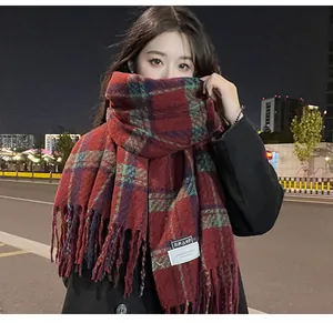 Close-up of red and green plaid cashmere scarf with tassels on a model at night