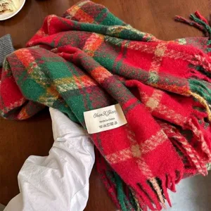 Festive Christmas red and green plaid scarf with tassels displayed on wooden table