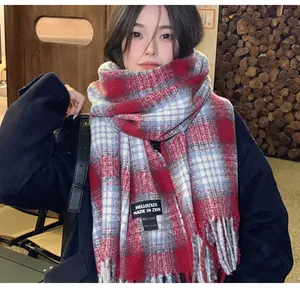 Detail shot of a cozy red and white plaid cashmere-like scarf featuring soft fringe