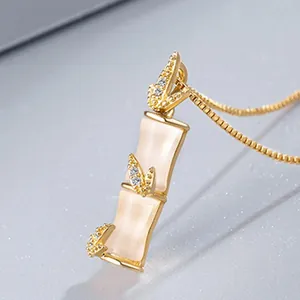 Gros plan d'un pendentif élégant en forme de bambou doré avec des pierres d'opale blanche