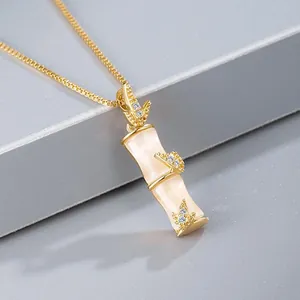 Gros plan d'un pendentif en forme de bambou doré avec des incrustations de pierres blanches.
