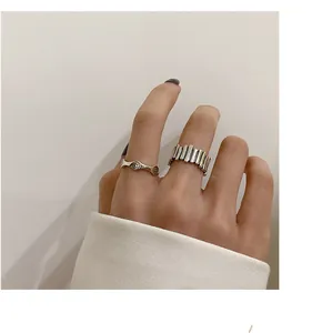 Close-up detail of a minimalist silver wavy smiley ring and a textured fence band ring.