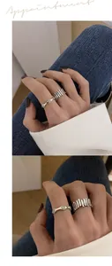 Detailed view of minimalist silver smiley face wavy ring and fence style band ring