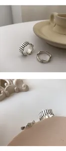 Close-up of sterling silver smiley face wave and fence design rings on minimalist background