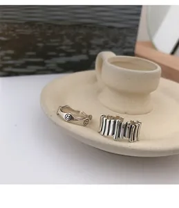 Close-up of silver rings featuring smiley face engravings and unique fence-style designs.
