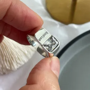 Detailed macro view of silver ring with square clear gemstone and Good Luck engraving