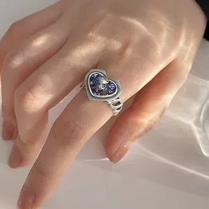 Detailed close-up of a niche design heart-shaped purple crystal ring worn on a finger