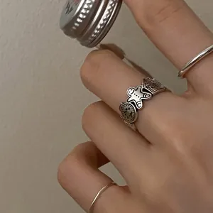 Close-up detail of a vintage silver gingerbread man ring worn on a model's finger.