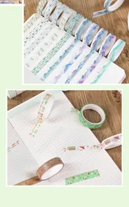 Close-up of decorative washi tapes applied to a grid notebook on a wooden desk