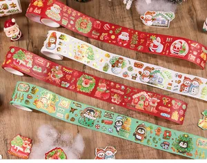 Dettaglio di rotoli di nastro washi natalizio con illustrazioni di pupazzo di neve e babbo.