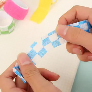 Vista detallada de manos rasgando una venda elástica autoadhesiva para dedos con cuadros azules