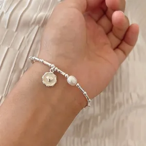 Vista dettagliata di un bracciale argento stile bambù con ciondolo a cuore e perla
