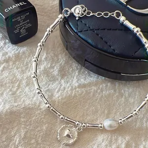 Dettaglio di un braccialetto a cuore in bambù argento con un delicato ciondolo di perla.
