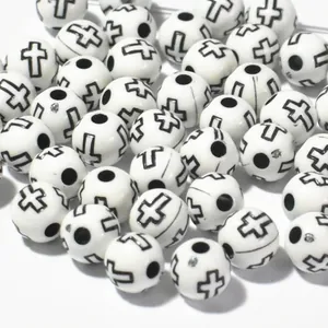 Close-up of 8mm white acrylic beads featuring black cross patterns for DIY crafts