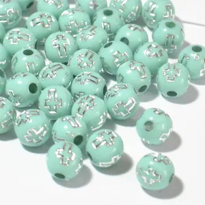 Detailed macro view of 8mm mint green acrylic beads featuring silver cross pattern designs