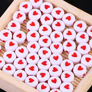 Primo piano di perline di acrilico bianco con cuore rosso per gioielli fai da te