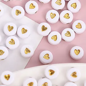 Vista dettagliata di perle acriliche bianche da 7 mm con motivo a cuore dorato per gioielli DIY.