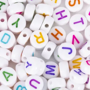 Macro detail of white acrylic 4x7mm alphabet beads with colorful letter patterns for DIY