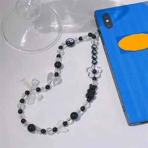 Detailansicht eines handgemachten Handybandes aus schwarzen und klaren Acrylperlen mit FAFA-Letters