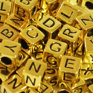 Macro detail of 6mm gold acrylic square alphabet letter beads for DIY jewelry making crafts