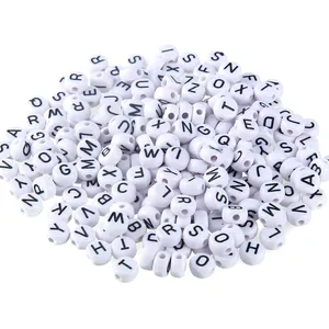Close-up of white acrylic alphabet beads with black letters for DIY jewelry making.