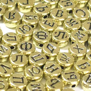 Primo piano di perline in acrilico dorato da 7mm con lettere cirilliche nere