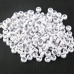 Macro detail of 4x7mm white acrylic letter beads with black A-Z alphabet print