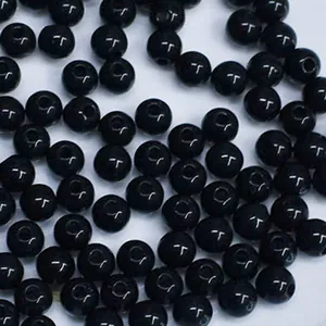 Detailed close-up macro view of glossy black acrylic round beads with straight center holes
