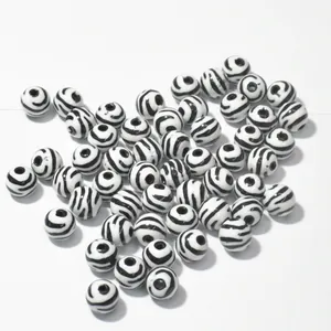 Macro detail of round acrylic beads with black and white zebra stripe patterns for DIY
