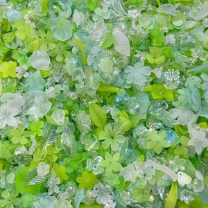Close-up of mixed green iridescent acrylic flower and leaf beads for DIY jewelry making.