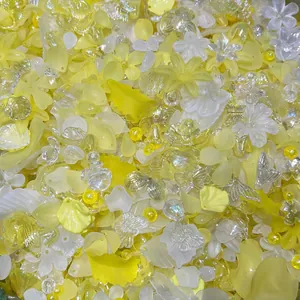 Detailed macro view of mixed yellow and iridescent acrylic flower and leaf beads for DIY.
