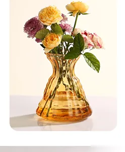 Dettaglio di un vaso in vetro ambrato con rose gialle vivaci e fiori freschi misti