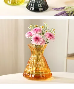 Dettaglio del vaso in vetro ambrato con fiori rosa in un ambiente domestico moderno