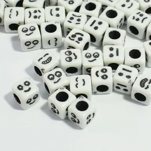 Close-up of 6mm white acrylic cubic beads with black smile face patterns for DIY crafts