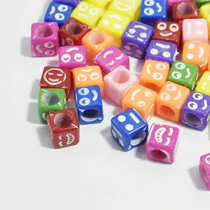 Macro shot of colorful 6mm acrylic square beads with engraved white smiley faces